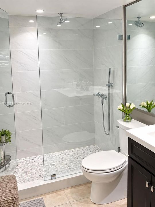Walk-in shower with floor-to-ceiling large-format tile surround, frameless glass enclosure, pebble-stone flooring, and handheld shower fixture