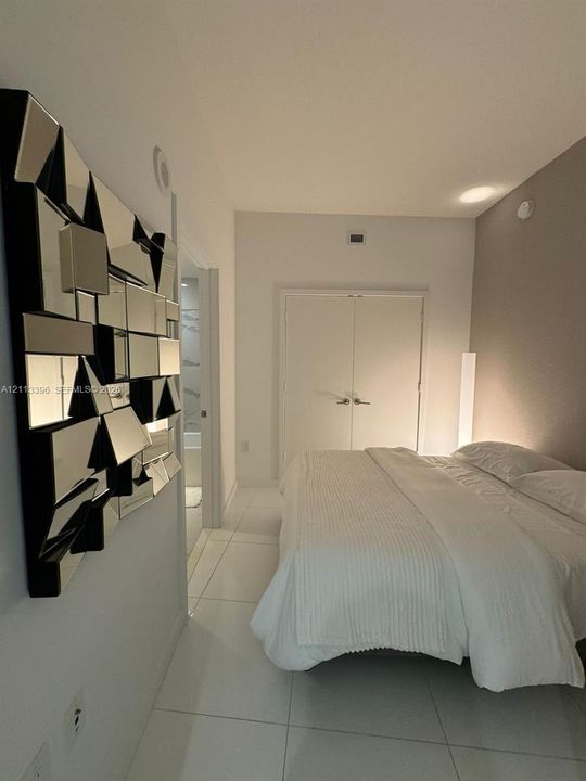 Neutral-toned room featuring large-format tile flooring, a double-door reach-in closet, and a recessed ceiling light