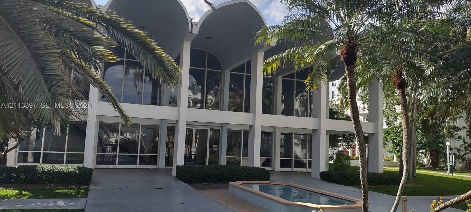 Exterior facade featuring multi-story arched concrete columns, expansive floor-to-ceiling windows, and a built-in water feature