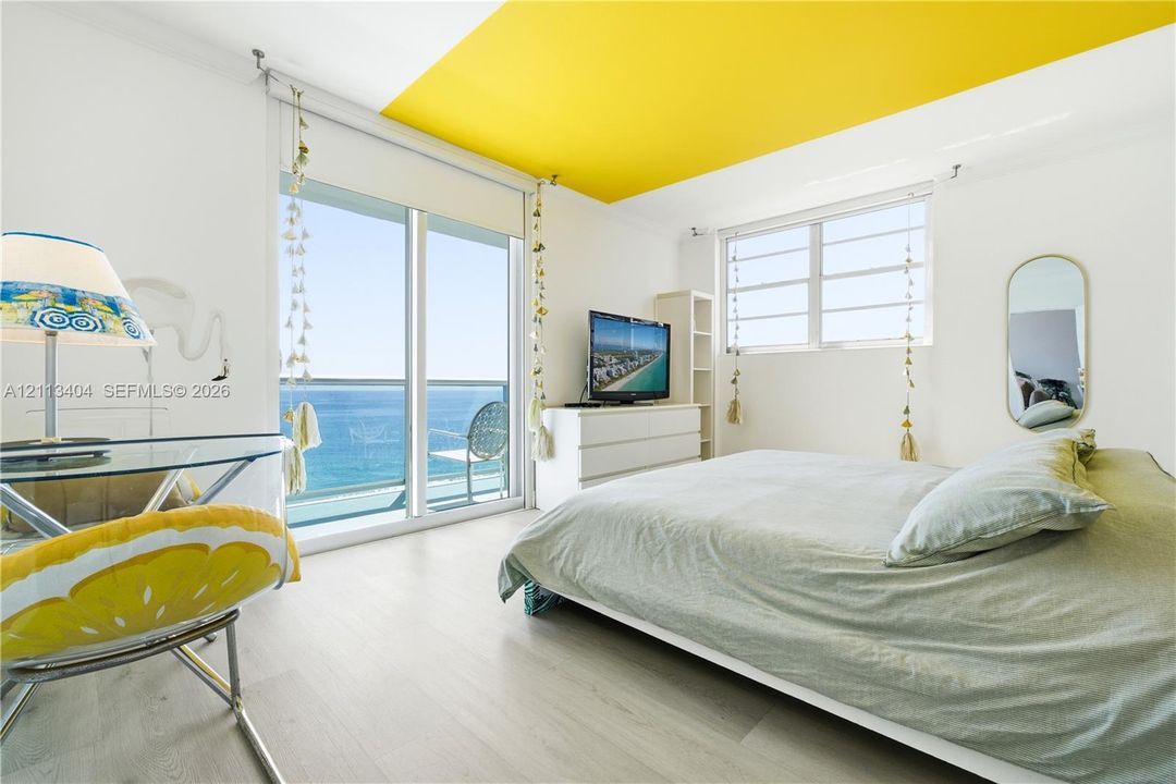 Floor-to-ceiling sliding glass door, white wood-finish flooring, accent-painted ceiling, and horizontal pane windows