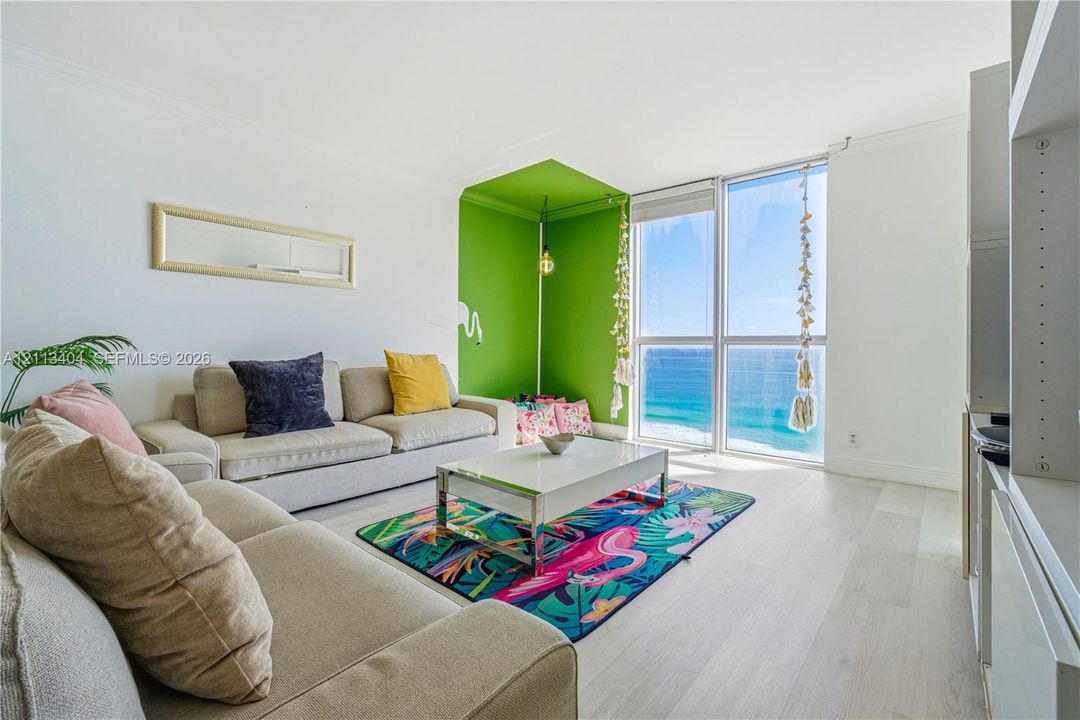 Floor-to-ceiling windows featuring ocean horizon, wood-finish flooring, and built-in shelving