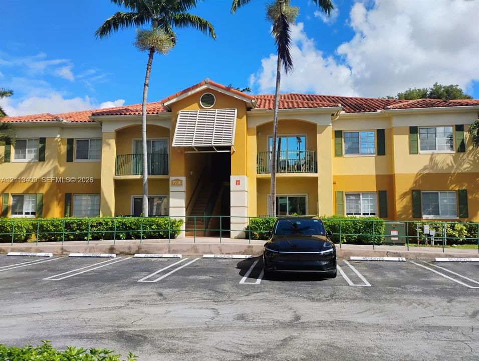 Two-story exterior featuring a clay tile roof, stucco finish, decorative shutters, and private railed balconies