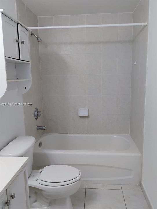 Full bathroom featuring a tub and shower combination with tile surround, white cabinetry, and ceramic tile flooring
