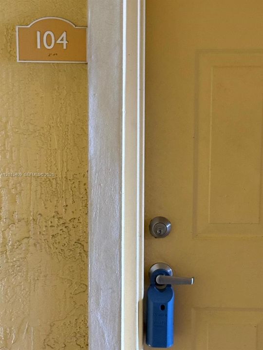 Textured exterior wall finish, solid door with panel detailing, stainless steel deadbolt, and lever-style handle