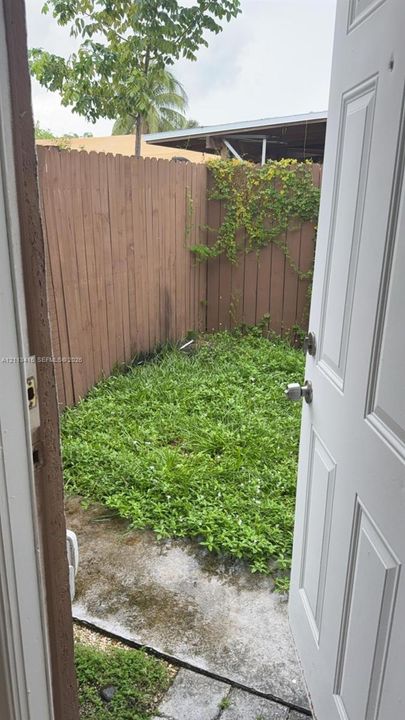 Outdoor space enclosed by vertical wood fencing and featuring a concrete patio slab