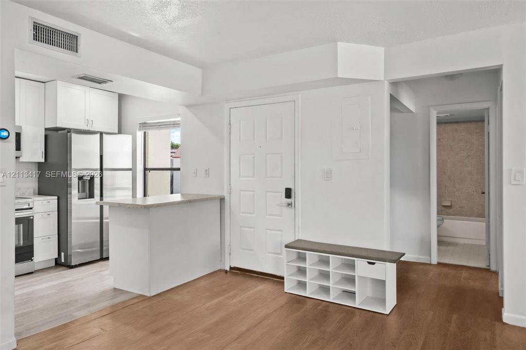 Kitchen area featuring white cabinetry, a countertop peninsula, and stainless steel refrigerator
