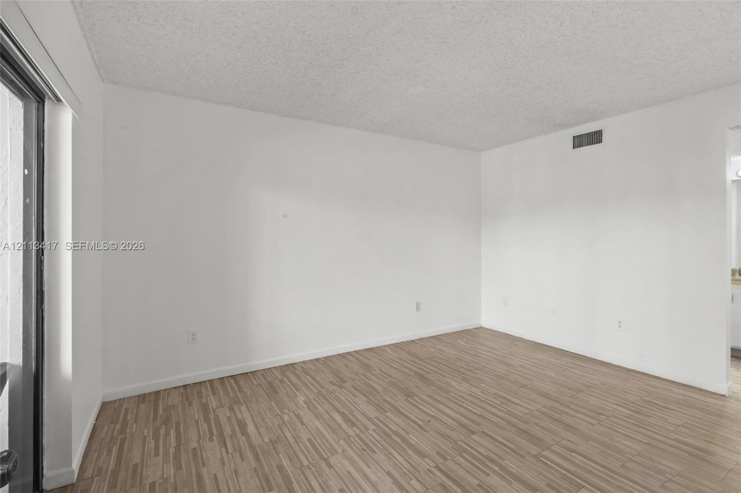 Neutral-toned interior space featuring wood-finish flooring and access to an exterior entry