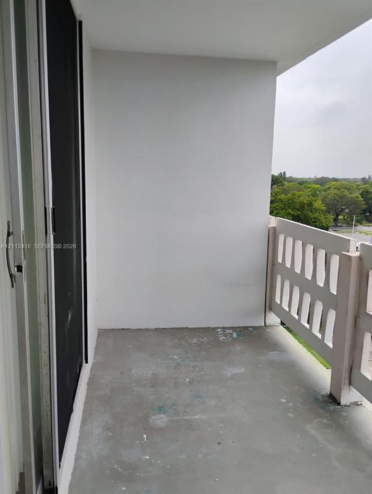 Private balcony featuring concrete flooring, a decorative lattice-style railing, and sliding glass entry door