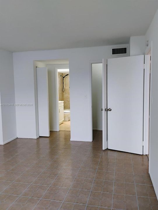 Neutral-toned square tile flooring, solid-core interior doors, and minimalist white wall finishes