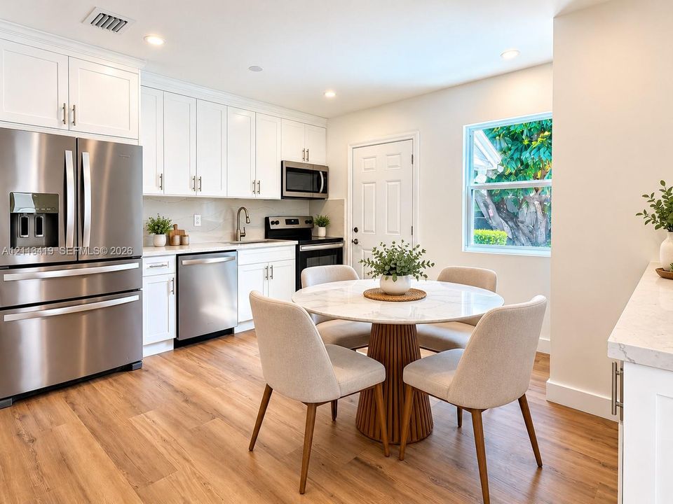 Virtually staged kitchen featuring white shaker-style cabinetry, stainless steel appliances, neutral countertops, and wood-finish flooring