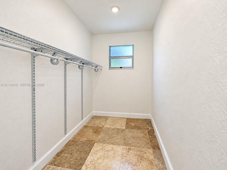 Storage area featuring wire shelving, large-format tile flooring, and a window