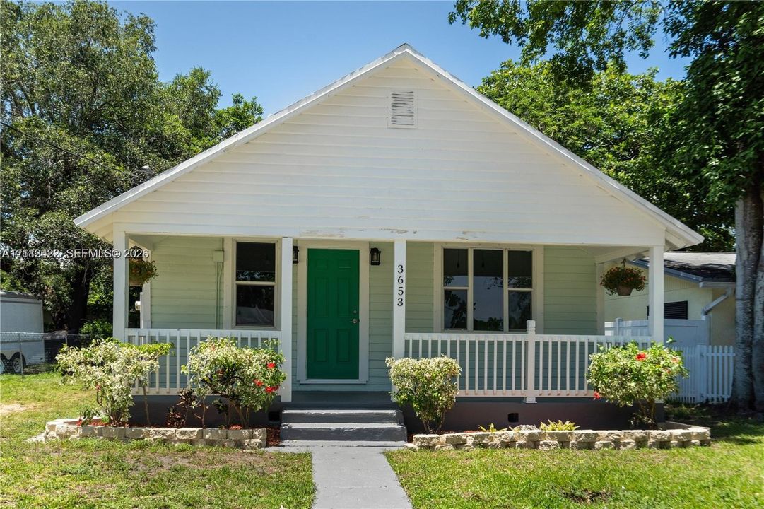 Exterior featuring light green horizontal siding, a gabled roofline, a front porch with white railing, and a raised concrete foundation