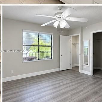 Wood-finish flooring, multi-blade ceiling fan with integrated lighting, and window with horizontal blinds
