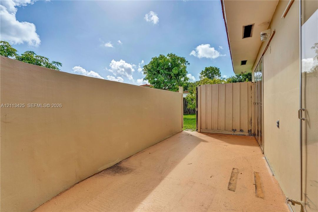 Outdoor patio featuring a concrete floor, stucco perimeter wall, and a vertical panel privacy screen