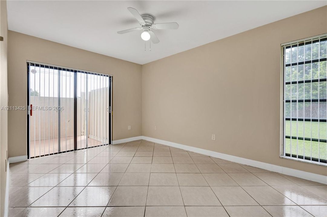 Room featuring tile flooring, a ceiling fan with integrated lighting, a sliding glass door, and a grid-patterned window