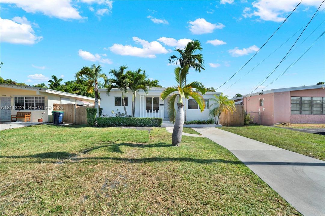 Single-story residence featuring a smooth stucco exterior, concrete driveway, and established palm trees