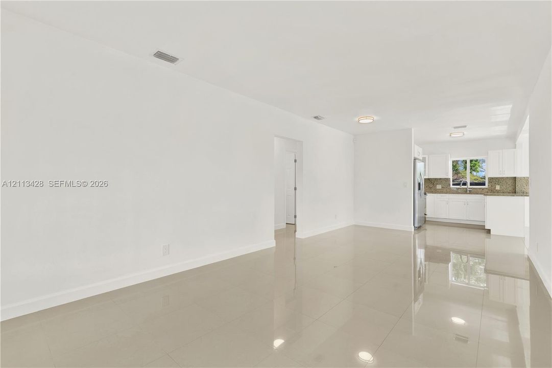 Neutral-toned tile flooring, white cabinetry, integrated stone-finish countertops, and flush-mount ceiling lighting
