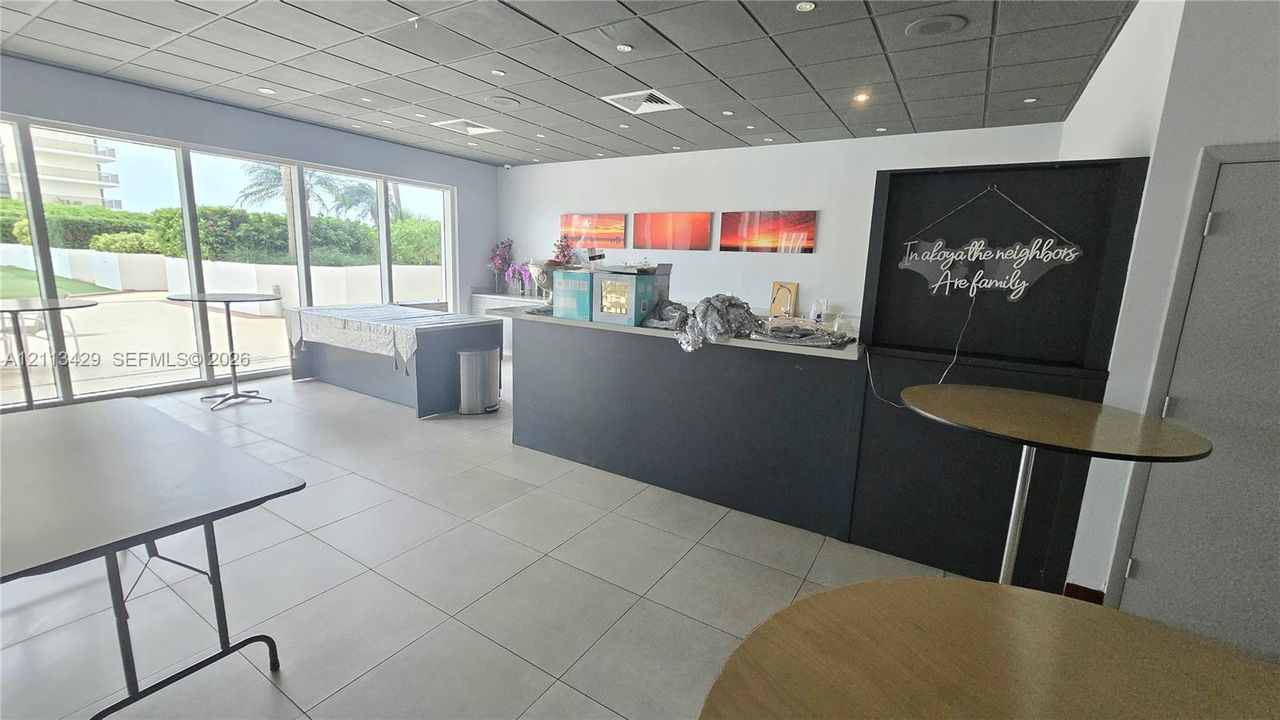 Large-format tile flooring, expansive floor-to-ceiling windows, and built-in service counter with solid surface countertop