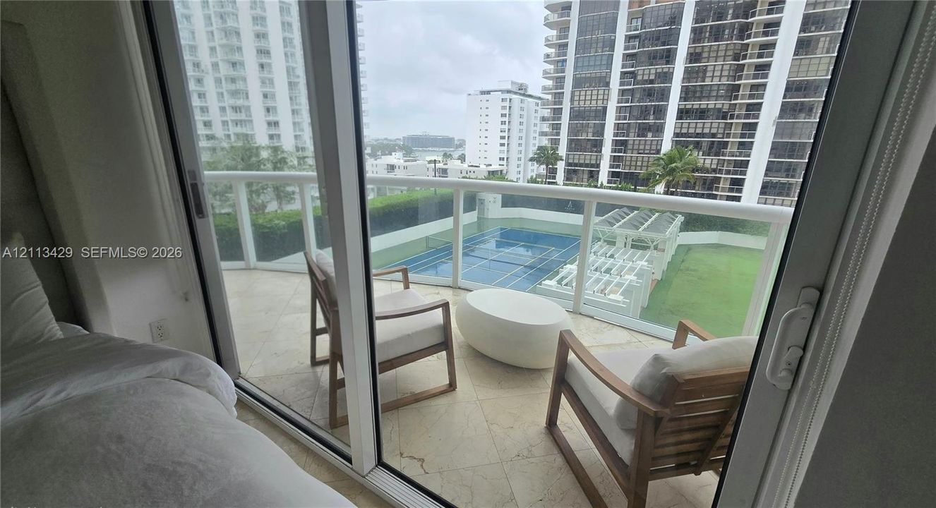 Private balcony featuring stone tile flooring and a glass panel railing