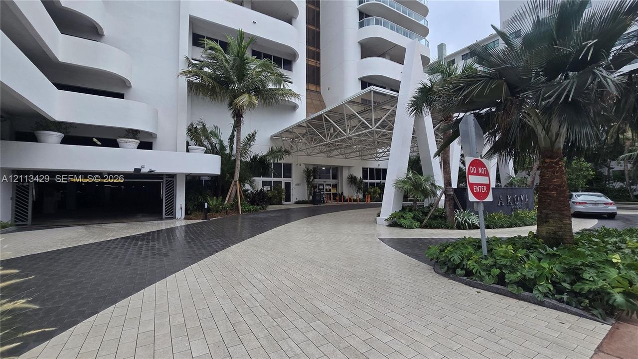 Building exterior featuring a geometric porte-cochère, paved circular motor court, and covered parking entrance