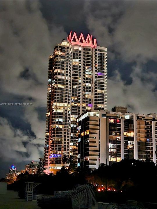 High-rise architectural structure featuring a prominent crown roof design, stacked balconies, and expansive glass exterior glazing