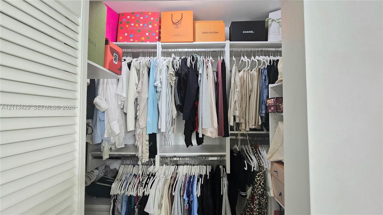 Custom closet organization system featuring white laminate shelving, adjustable vertical supports, and dual-level hanging rods