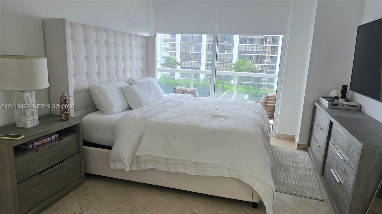 Floor-to-ceiling windows featuring automated roller shades, neutral stone flooring, and expansive natural light