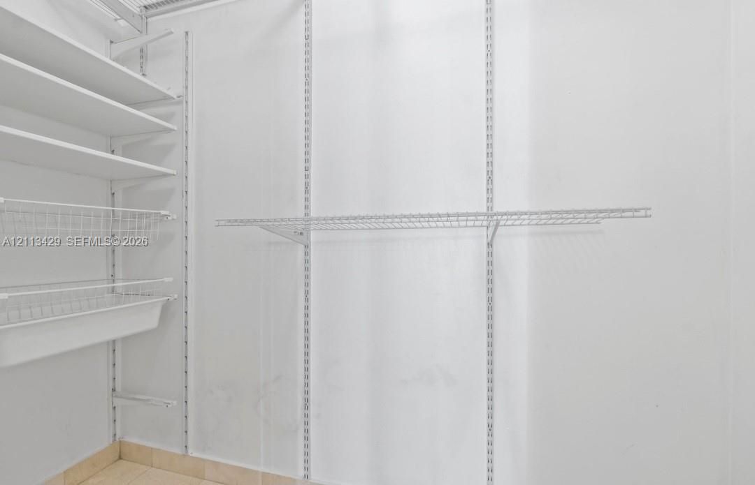 Customizable white wire shelving system featuring tiered shelves, integrated wire baskets, and vertical adjustable track supports