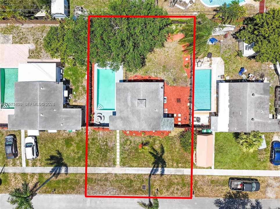 Aerial perspective of property featuring an in-ground swimming pool, concrete patio, mature trees, and perimeter fencing