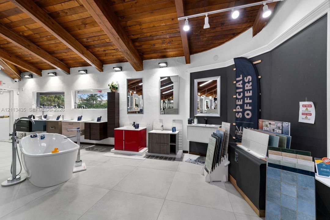 Vaulted wood-beam ceiling, large-format tile flooring, exposed-beam architecture, and wall-mounted track lighting