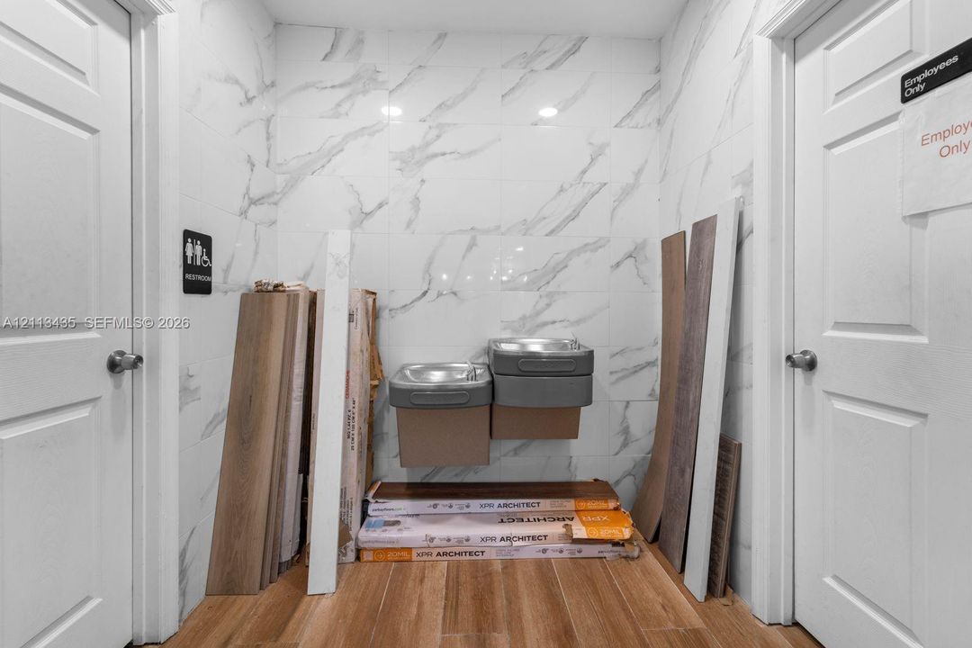 Wall-mounted dual-level drinking station featuring large-format tile wall cladding and wood-finish flooring