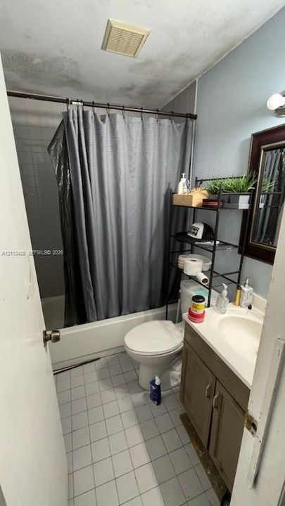 Bathroom featuring a porcelain vanity with a built-in sink, a standard tub and shower combination, ceramic tile flooring, and a wall-mounted medicine cabinet