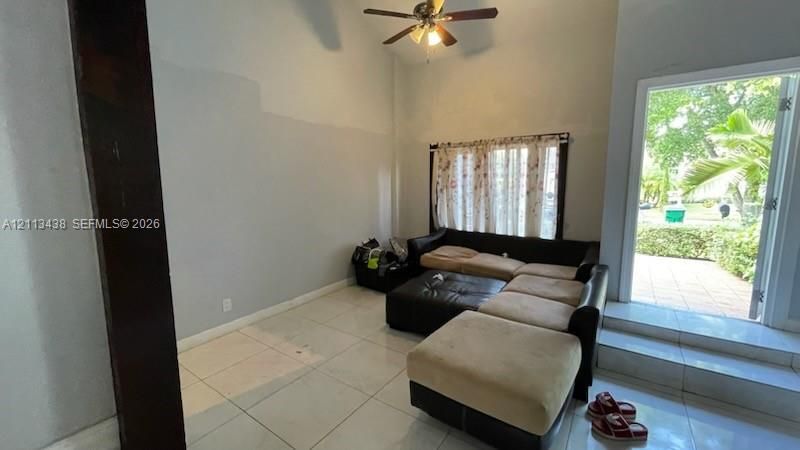 Vaulted ceilings, large-format tile flooring, ceiling fan, and access to exterior patio space