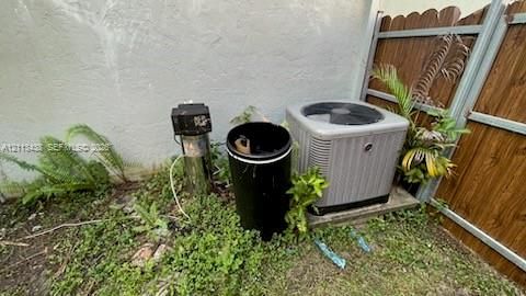 Exterior HVAC condenser unit mounted on a concrete pad, accompanied by a residential water treatment system and wood-finish privacy fencing