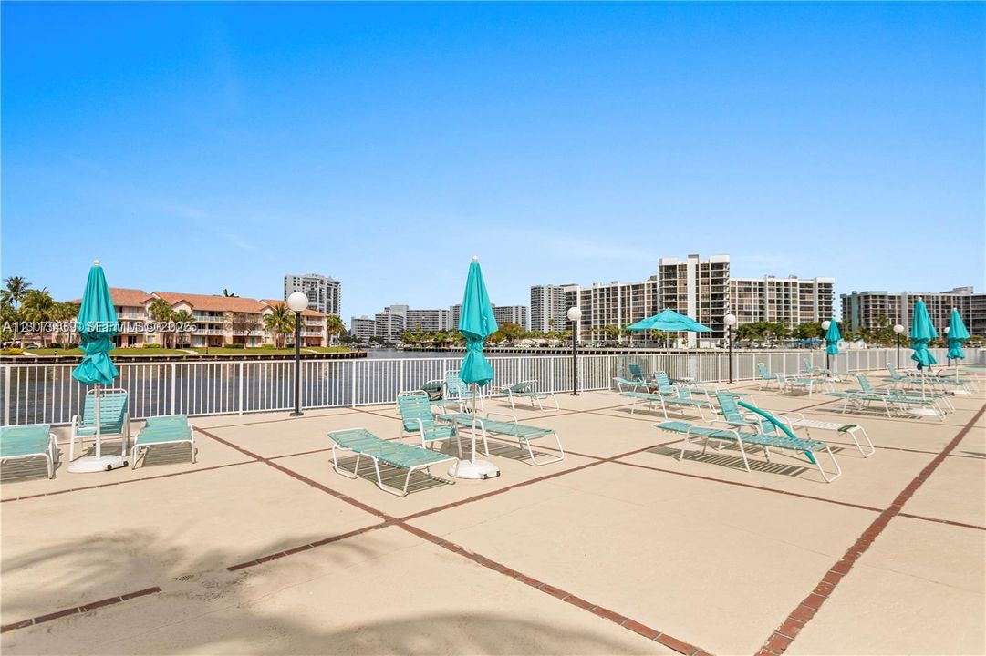 Waterfront deck featuring a concrete paver surface, white metal perimeter fencing, and integrated globe-style lighting