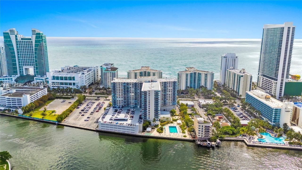 Aerial perspective of the coastline featuring high-rise buildings, multiple outdoor swimming pools, and extensive waterfront frontage