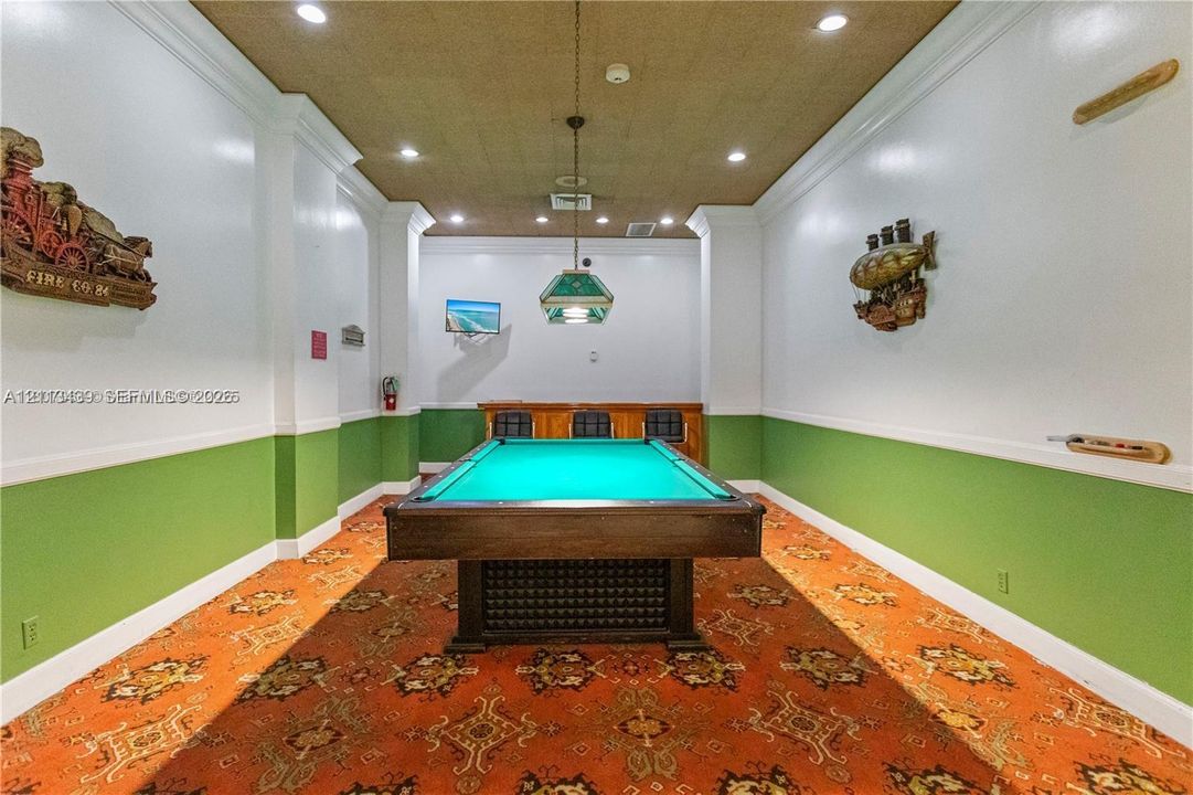 Game room featuring a built-in wooden bar, recessed ceiling lighting, a suspended decorative light fixture, and crown molding