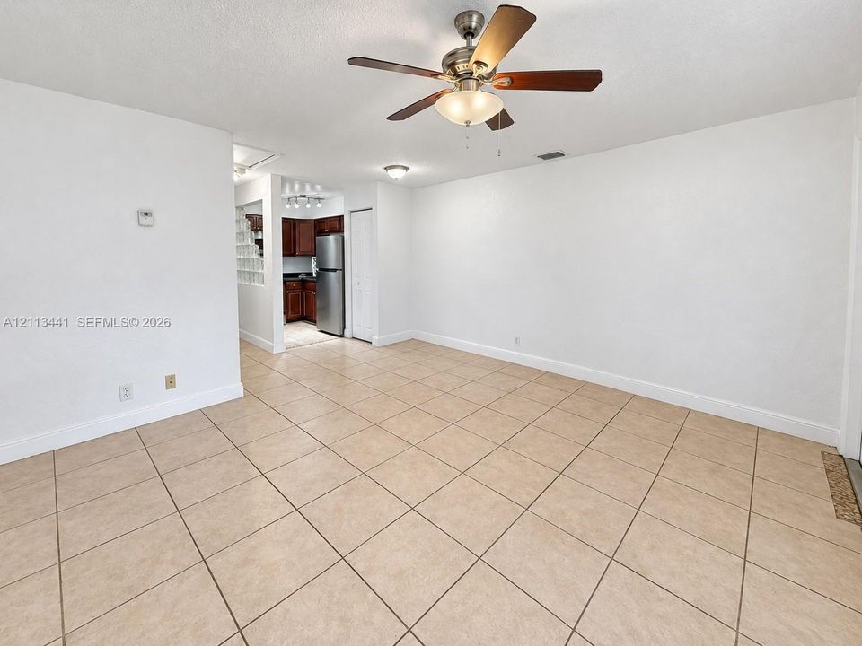 Neutral ceramic tile flooring, ceiling fan with integrated lighting, and smooth-finish walls