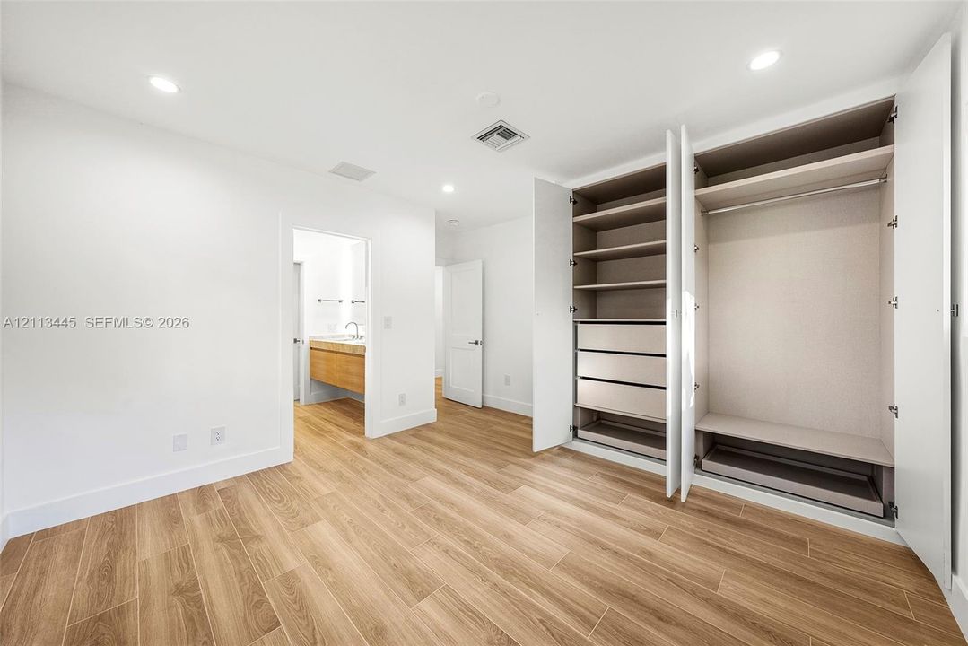 Wood-finish flooring, built-in wardrobe with integrated shelving and drawers, and recessed lighting