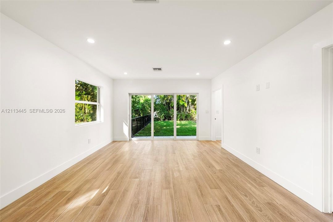 Interior space featuring wood-finish flooring, recessed lighting, a single-pane window, and large sliding glass doors providing access to the exterior