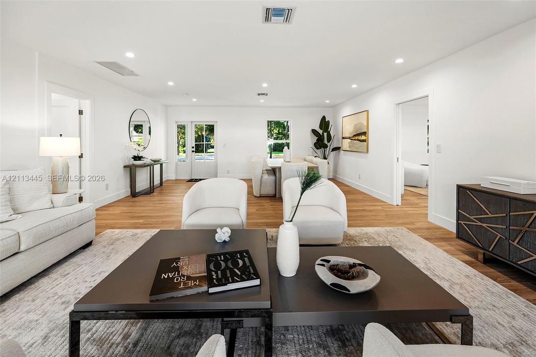 Open-concept interior featuring wood-finish flooring, recessed lighting, and a glass-paneled entry door