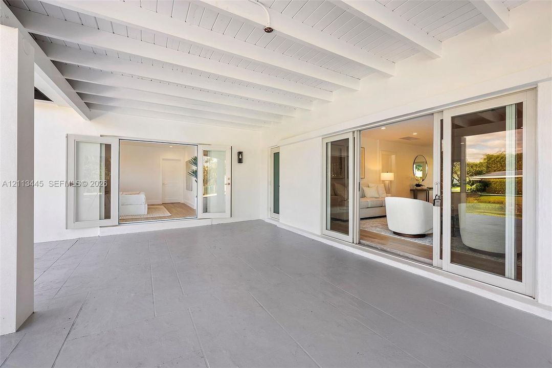 Covered patio featuring an exposed-beam ceiling, solid-surface flooring, and glass-paneled doors