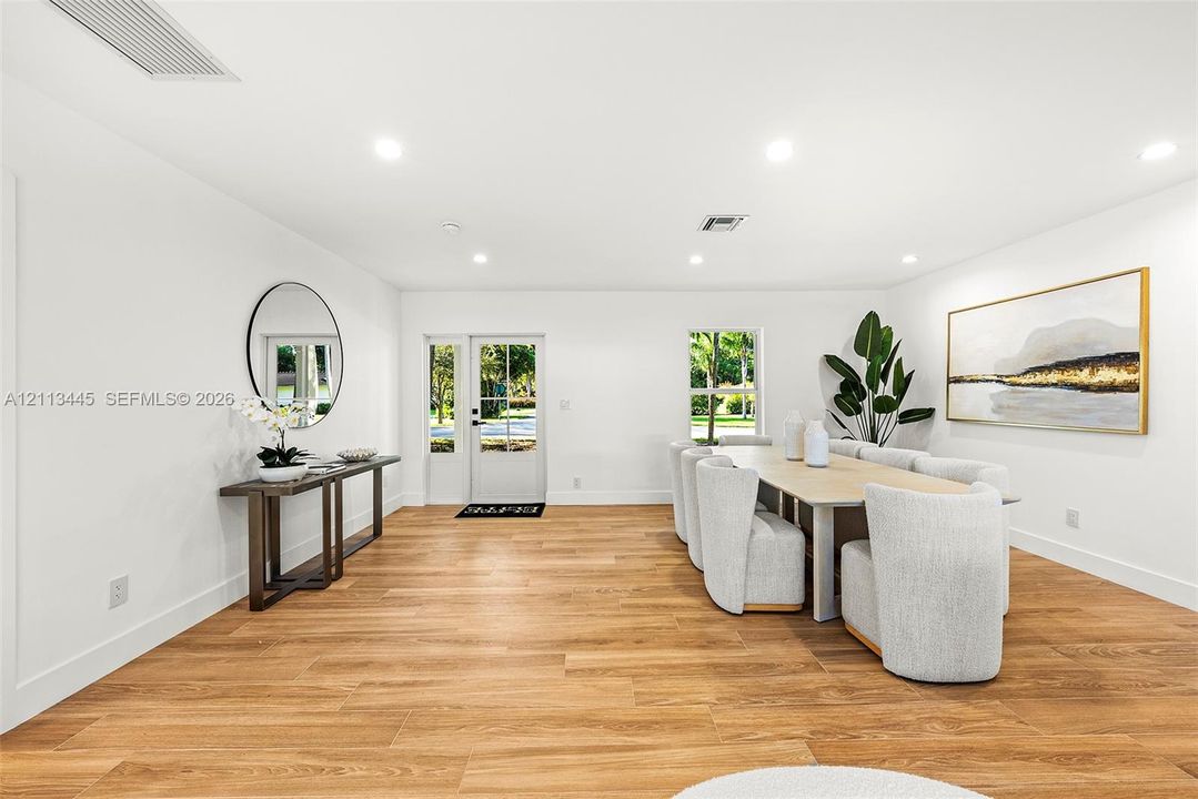 Open interior featuring wood-finish flooring, recessed lighting, and a white-framed glass paneled entry door