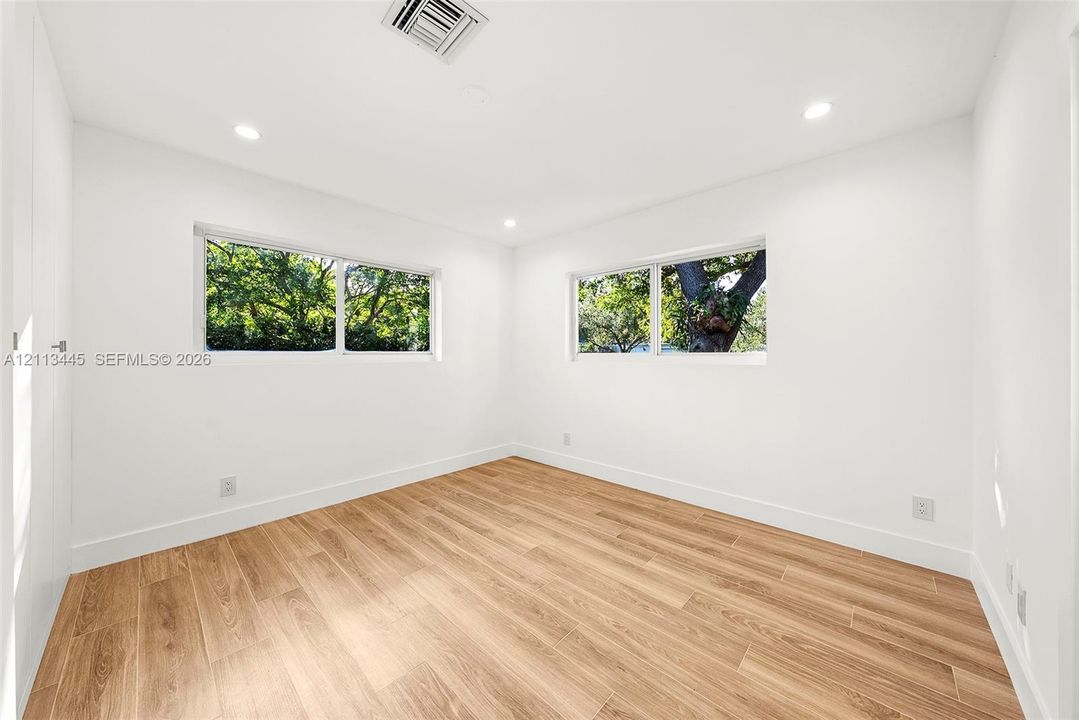 Room featuring wood-finish flooring, recessed lighting, and dual horizontal windows