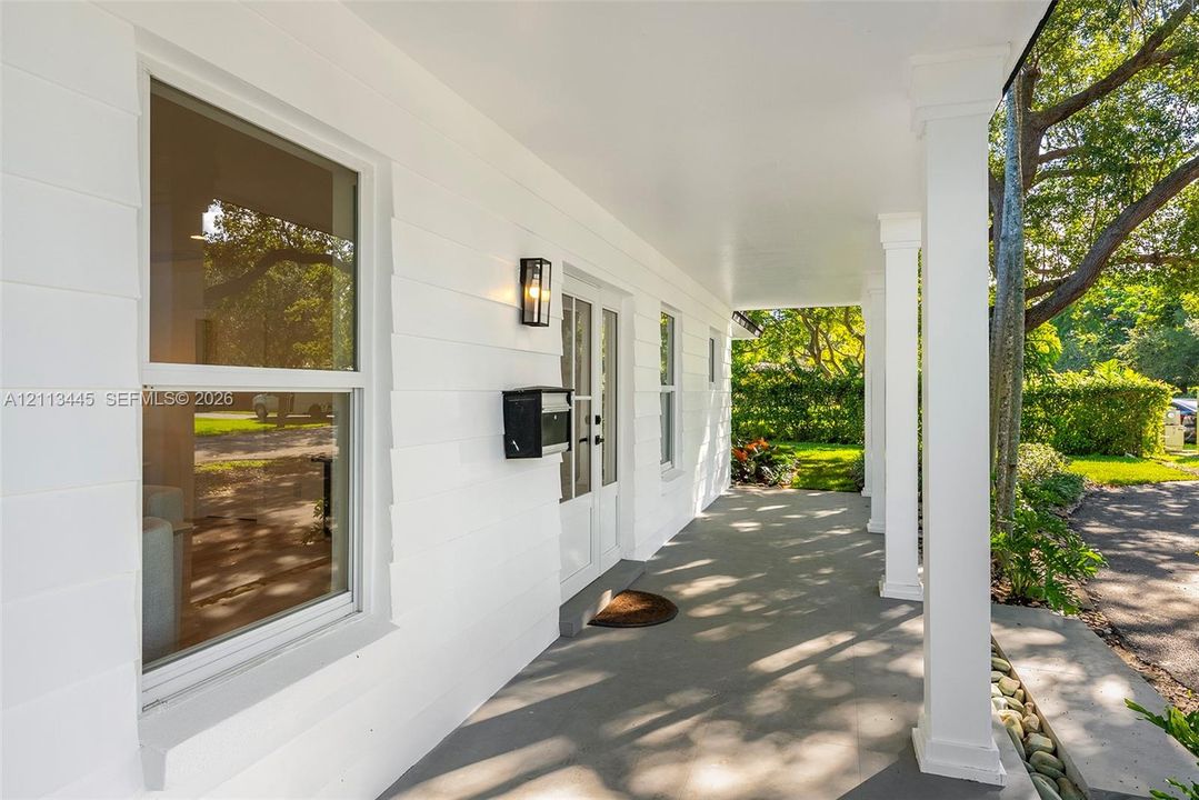 Covered front porch featuring smooth-finish ceiling, square structural columns, horizontal lap siding, wall-mounted exterior lighting, and double-entry doors