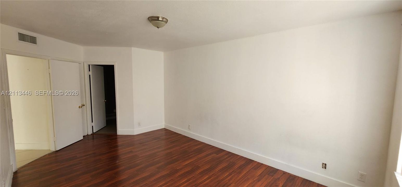 Interior space featuring wood-finish flooring, white walls, and a ceiling-mounted light fixture