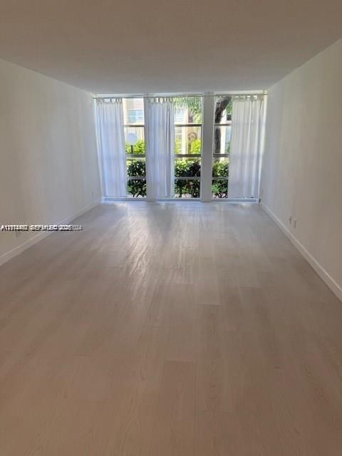 Open-concept interior featuring wood-finish flooring, neutral walls, and floor-to-ceiling windows