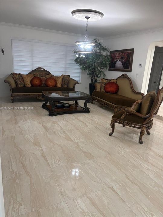 Large-format polished stone flooring, recessed ceiling medallion, and multi-tier hanging light fixture