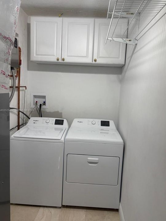 Laundry area featuring white cabinetry, a wall-mounted wire shelving unit, and dedicated washer and dryer hookups