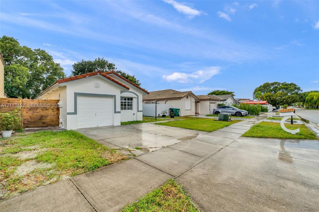 Single-story residence featuring a tile roof, an attached garage, and a wood-panel fence